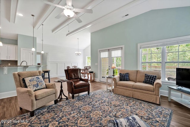 living room with plenty of natural light, dark wood finished floors, ceiling fan, a chandelier, and beamed ceiling