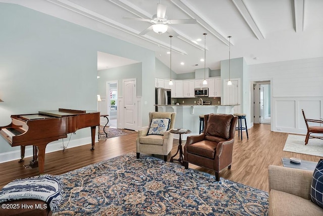 living area with light wood-style flooring, ceiling fan, and baseboards