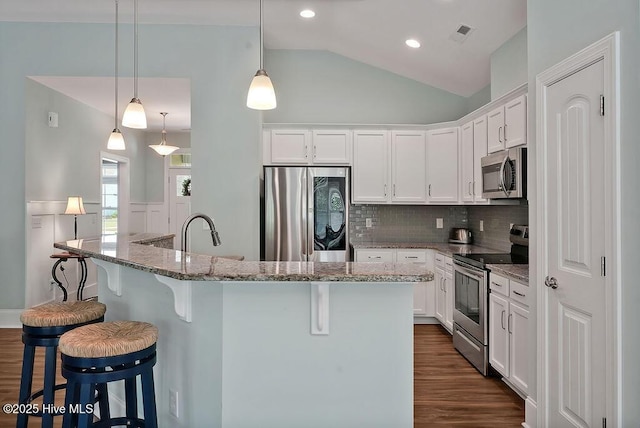 kitchen featuring stainless steel appliances, dark wood-style floors, lofted ceiling, a breakfast bar area, and recessed lighting
