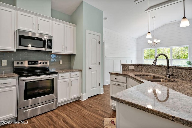 kitchen with stainless steel appliances, a sink, dark wood finished floors, white cabinets, and decorative backsplash
