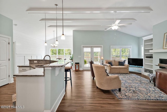 living room featuring a ceiling fan, healthy amount of natural light, dark wood-style flooring, and built in features