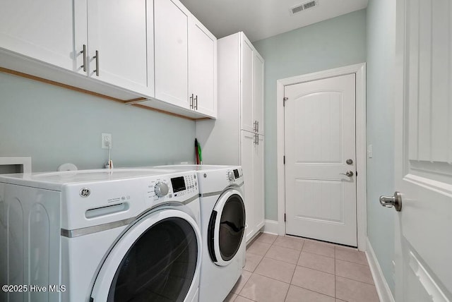 washroom featuring cabinet space, washer and clothes dryer, light tile patterned flooring, and baseboards