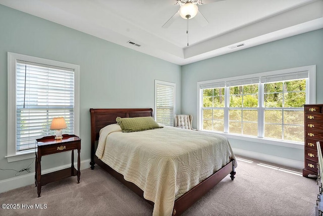 carpeted bedroom featuring baseboards, a ceiling fan, and a raised ceiling