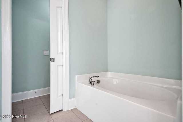 full bath with tile patterned flooring, a garden tub, and baseboards