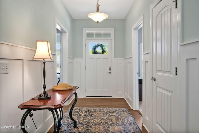 entrance foyer with a wainscoted wall, dark wood-type flooring, and a decorative wall