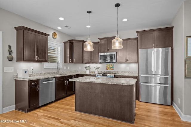 kitchen featuring a sink, light wood finished floors, dark brown cabinets, and appliances with stainless steel finishes