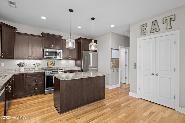 kitchen with a center island, appliances with stainless steel finishes, visible vents, and dark brown cabinets