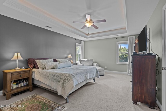 bedroom with a ceiling fan, baseboards, visible vents, a raised ceiling, and light carpet