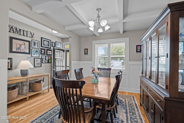 dining space with coffered ceiling, light wood-style floors, a wainscoted wall, and a notable chandelier