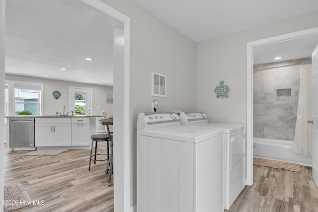 laundry room with washer and clothes dryer, light wood-style floors, recessed lighting, and a sink