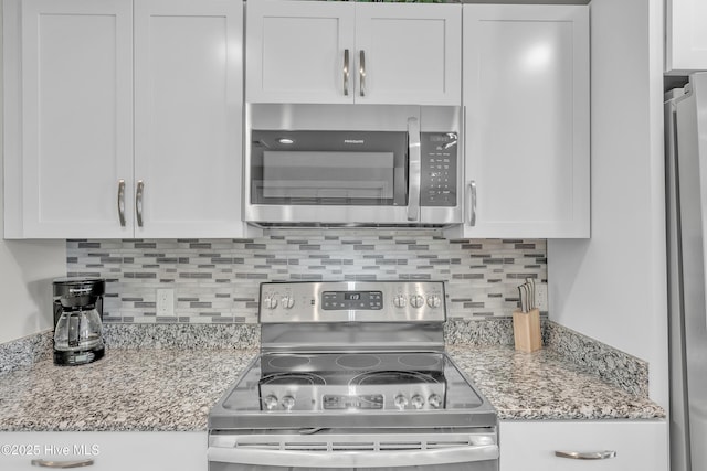 kitchen featuring stainless steel appliances, white cabinetry, and tasteful backsplash