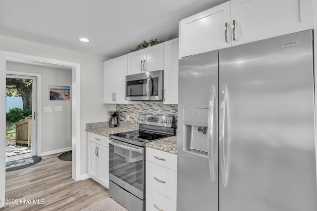 kitchen featuring appliances with stainless steel finishes, white cabinets, backsplash, light stone countertops, and recessed lighting