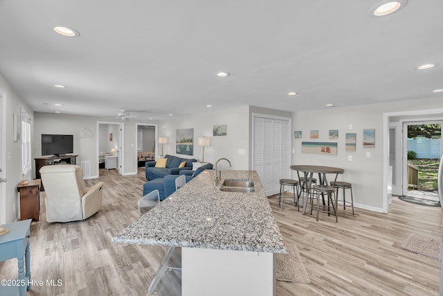living area with baseboards, light wood-style floors, recessed lighting, and a ceiling fan