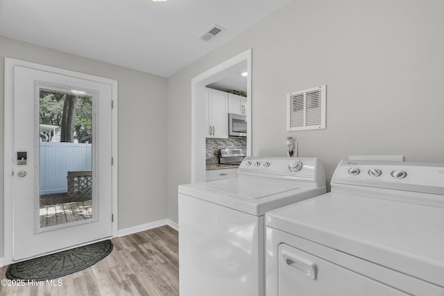 clothes washing area with washing machine and clothes dryer, light wood-style flooring, and baseboards