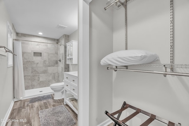 full bath featuring a stall shower, toilet, wood finished floors, baseboards, and recessed lighting