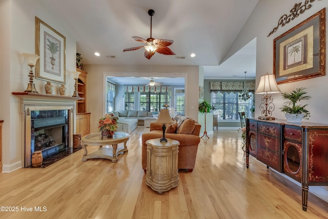 living room featuring light wood-type flooring, baseboards, a ceiling fan, and ornamental molding