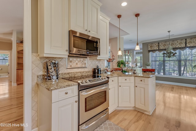 kitchen with light wood finished floors, light stone counters, stainless steel appliances, and a peninsula