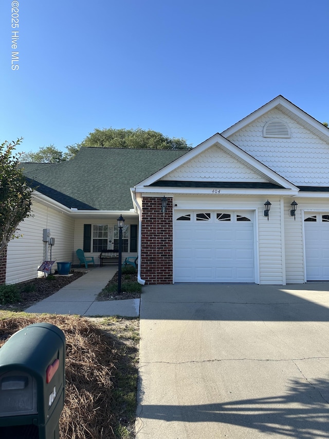 view of front of home featuring concrete driveway, a porch, brick siding, and a garage