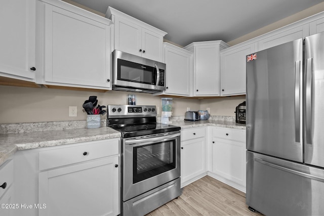 kitchen featuring white cabinets, appliances with stainless steel finishes, and light wood-style flooring