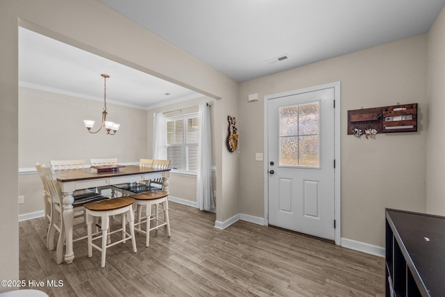 entryway featuring wood finished floors, a notable chandelier, crown molding, visible vents, and baseboards