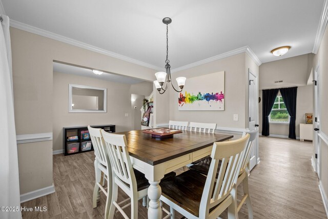 dining room with crown molding, light wood-style flooring, baseboards, and a notable chandelier