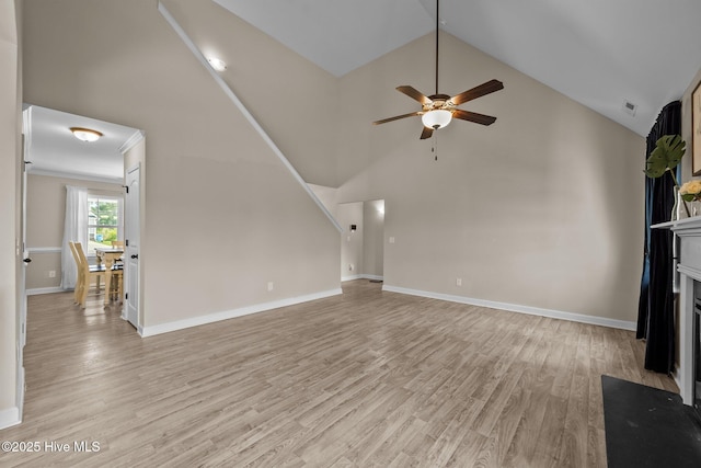 unfurnished living room featuring a ceiling fan, a fireplace with flush hearth, light wood finished floors, and high vaulted ceiling