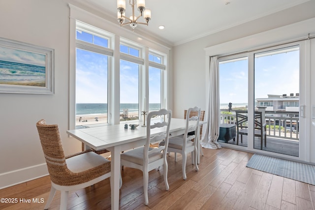26 Seagull St Unit B, Wrightsville Beach, NC 28480 - dining space with a chandelier, light wood finished floors, ornamental molding, a water view, and baseboards
