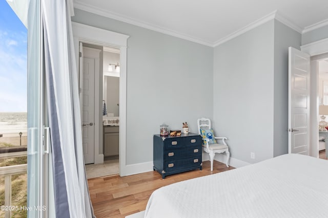 26 Seagull St Unit B, Wrightsville Beach, NC 28480 - bedroom featuring light wood-type flooring, crown molding, baseboards, ensuite bath, and a water view