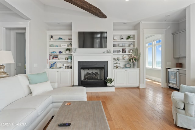 26 Seagull St Unit B, Wrightsville Beach, NC 28480 - living room featuring beverage cooler, light wood finished floors, ornamental molding, a fireplace with raised hearth, and beam ceiling