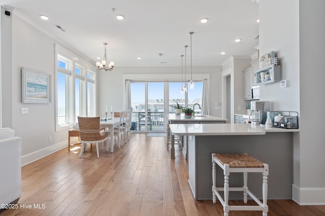 26 Seagull St Unit B, Wrightsville Beach, NC 28480 - kitchen with crown molding, a chandelier, light wood-type flooring, a breakfast bar area, and baseboards