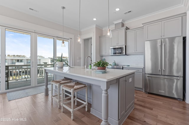 26 Seagull St Unit B, Wrightsville Beach, NC 28480 - kitchen featuring appliances with stainless steel finishes, gray cabinetry, ornamental molding, backsplash, and an island with sink