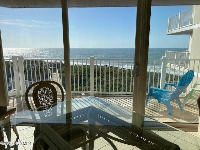 balcony with view of water and beach and outdoor dining area