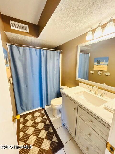 full bathroom with vanity, toilet, tile patterned floors, and a textured ceiling