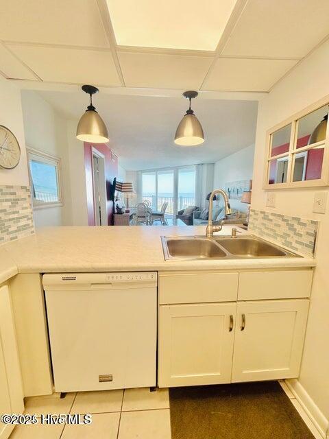 kitchen with dishwasher, a sink, white cabinetry, decorative backsplash, and a peninsula