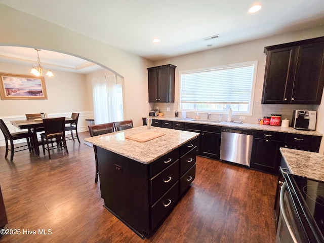 kitchen featuring visible vents, a sink, arched walkways, backsplash, and appliances with stainless steel finishes