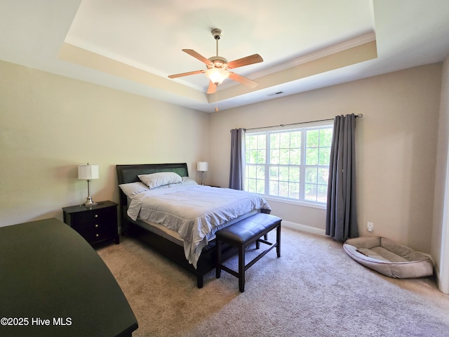 bedroom with ornamental molding, carpet, visible vents, ceiling fan, and a tray ceiling