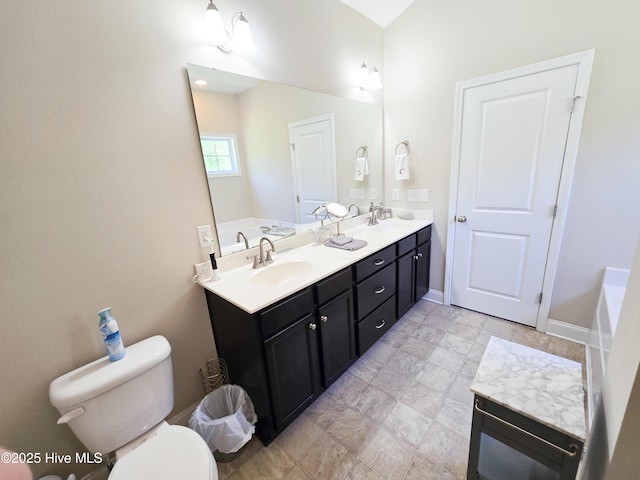 full bathroom with double vanity, toilet, a tub to relax in, and a sink