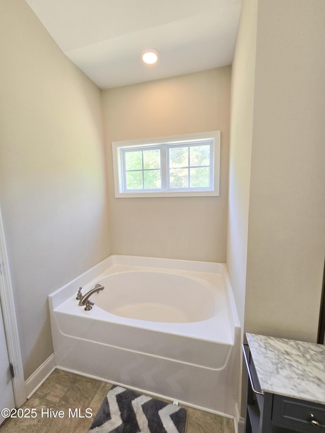 bathroom with tile patterned floors, a garden tub, and baseboards