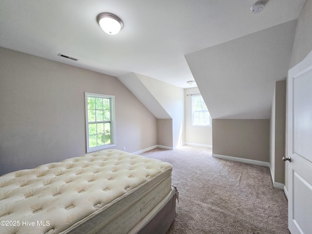carpeted bedroom with baseboards, visible vents, and vaulted ceiling