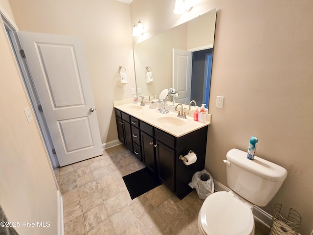 full bath with double vanity, toilet, baseboards, and a sink