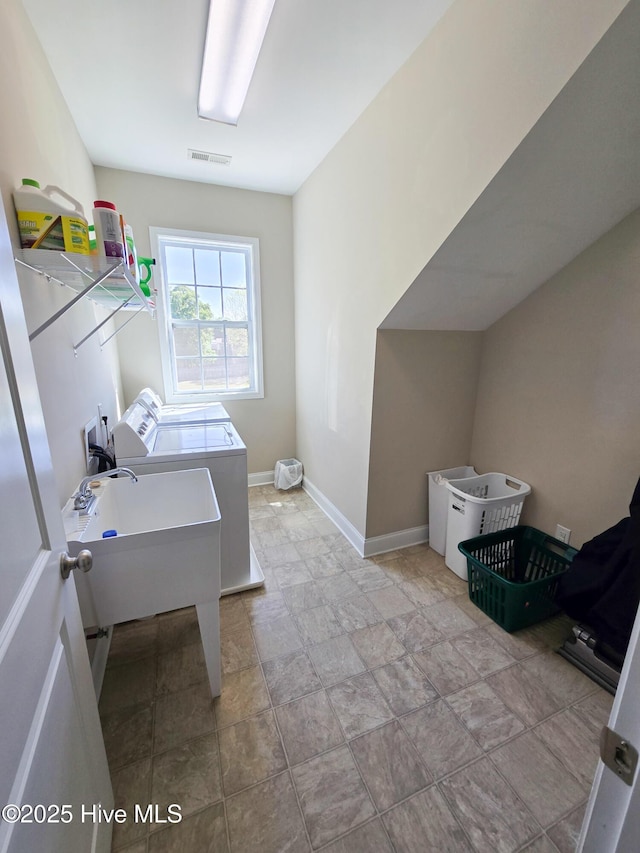 clothes washing area featuring laundry area, visible vents, stone finish flooring, washing machine and dryer, and baseboards