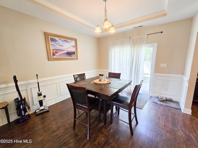 dining area with a tray ceiling, crown molding, visible vents, and dark wood finished floors