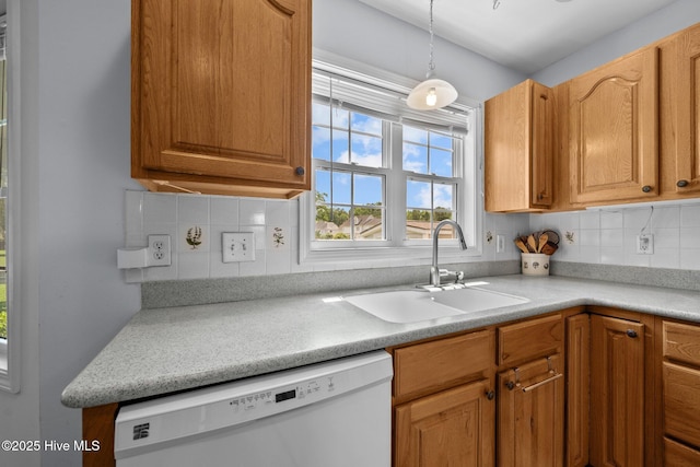kitchen featuring white dishwasher, a sink, decorative backsplash, light countertops, and brown cabinets