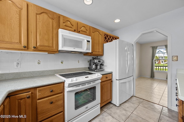 kitchen featuring white appliances, decorative backsplash, light countertops, light tile patterned floors, and brown cabinets