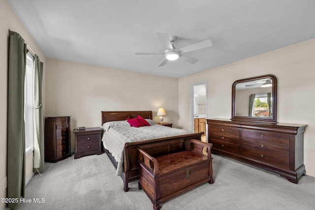 bedroom with light colored carpet, ensuite bathroom, and ceiling fan