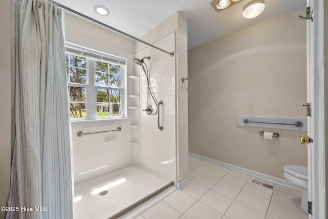 bathroom with a shower with shower curtain, tile patterned flooring, toilet, and baseboards