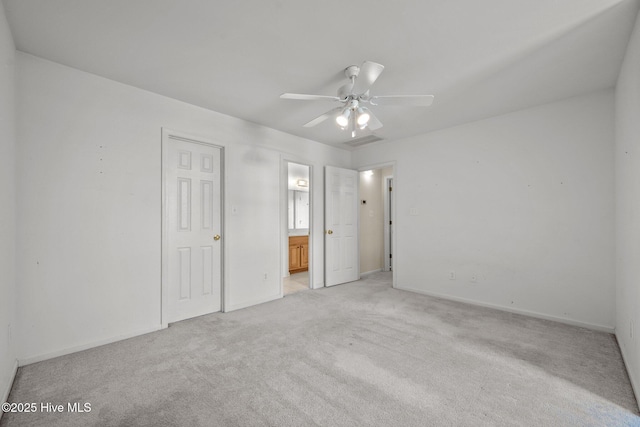 unfurnished bedroom featuring light colored carpet, baseboards, ensuite bath, and ceiling fan