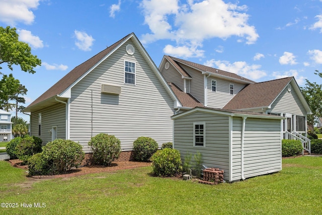 back of house with an outbuilding, a shed, a lawn, and roof with shingles