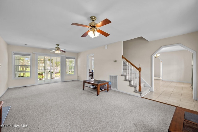 living room featuring ceiling fan, baseboards, stairway, and arched walkways