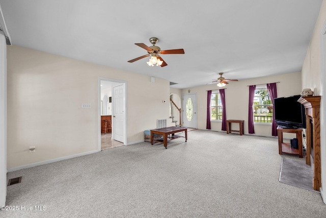 living room featuring a ceiling fan, light carpet, stairs, and baseboards